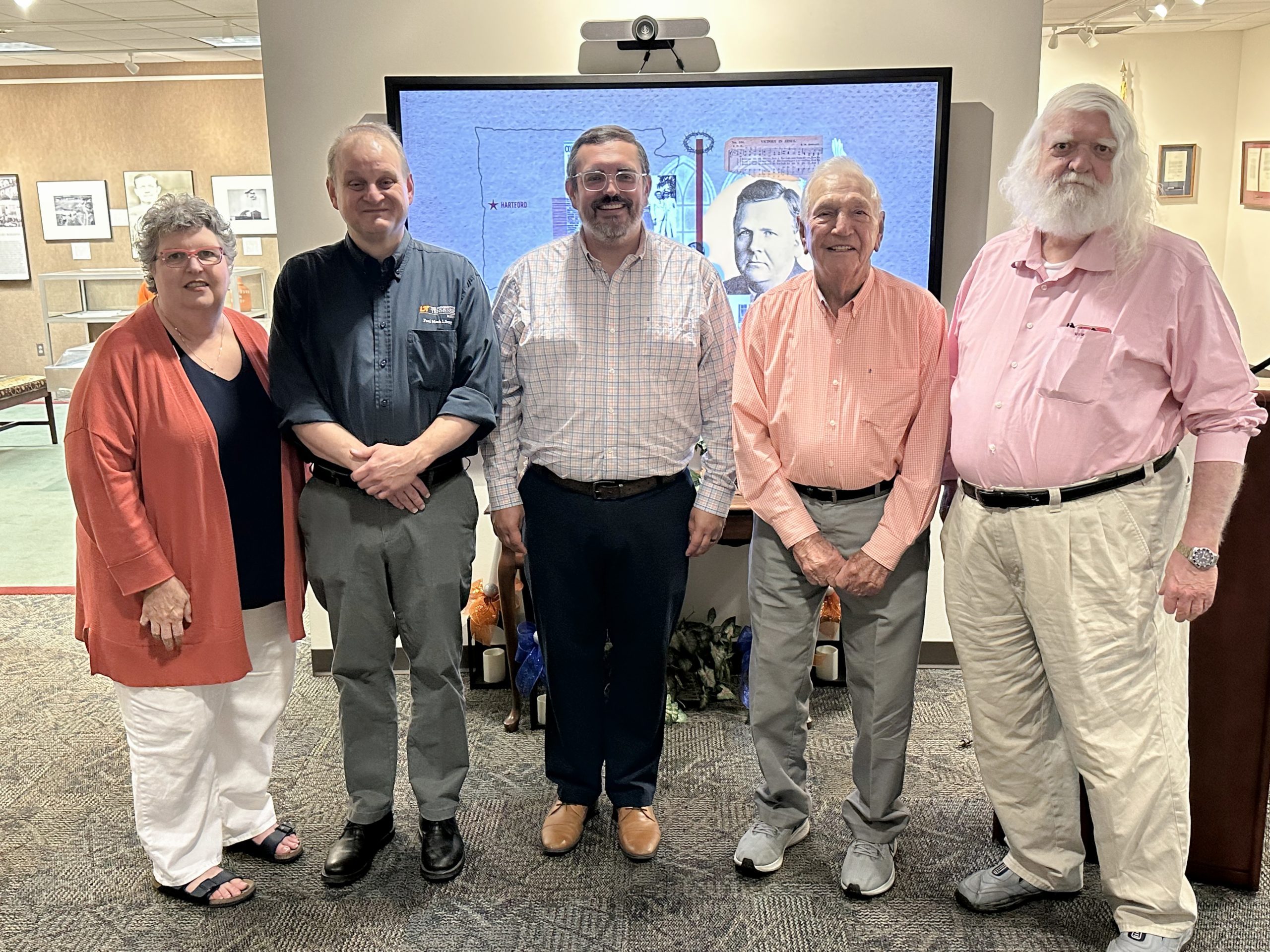 Five people are posted in front of a projection screen.