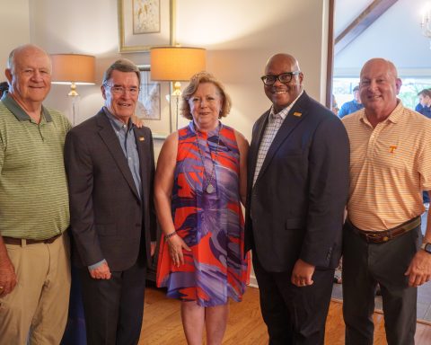 Five people are posed at a reception.