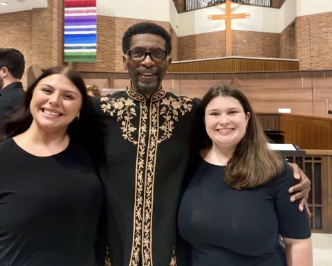 A man and two women are posed at an event.