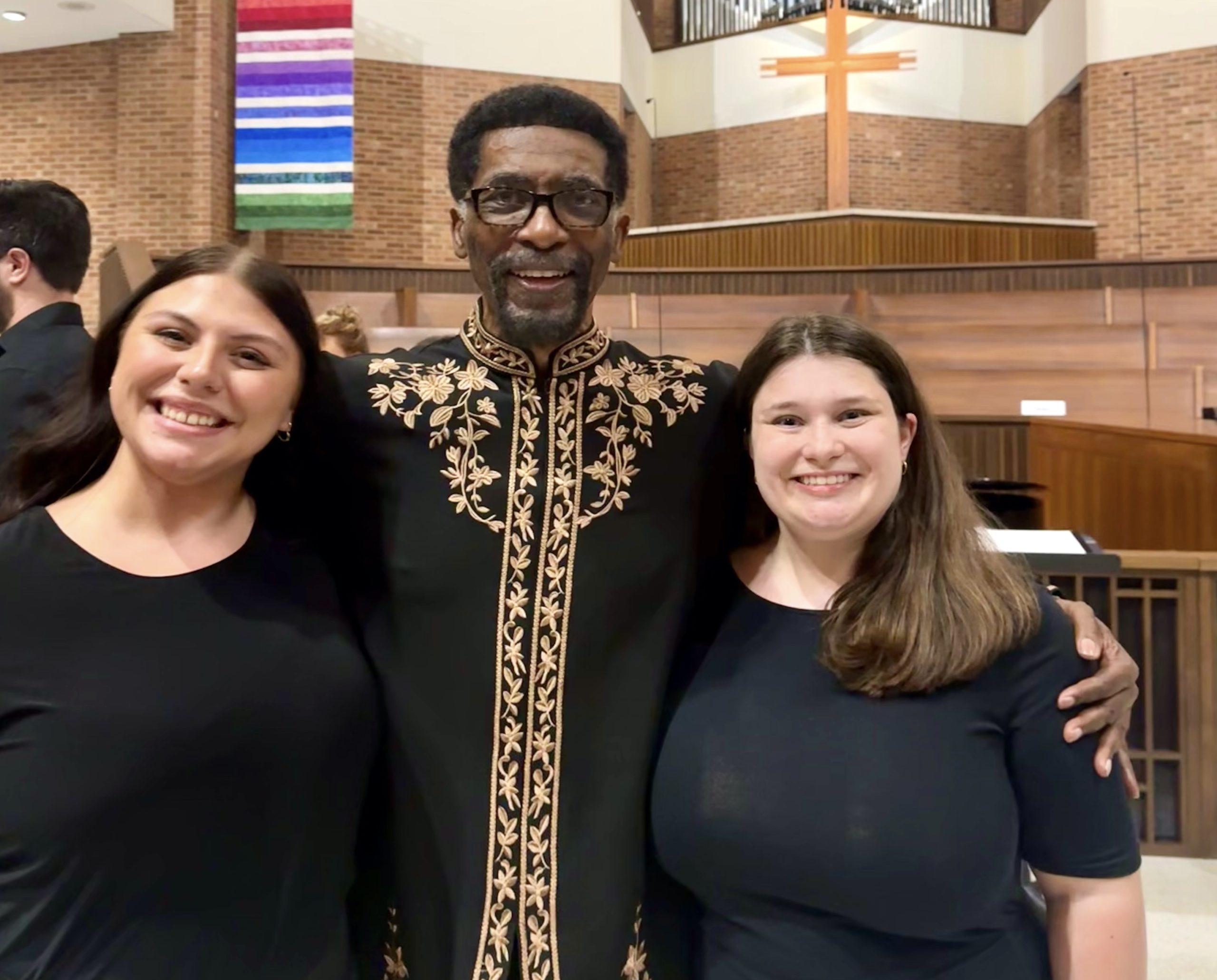 A man and two women are posed at an event.