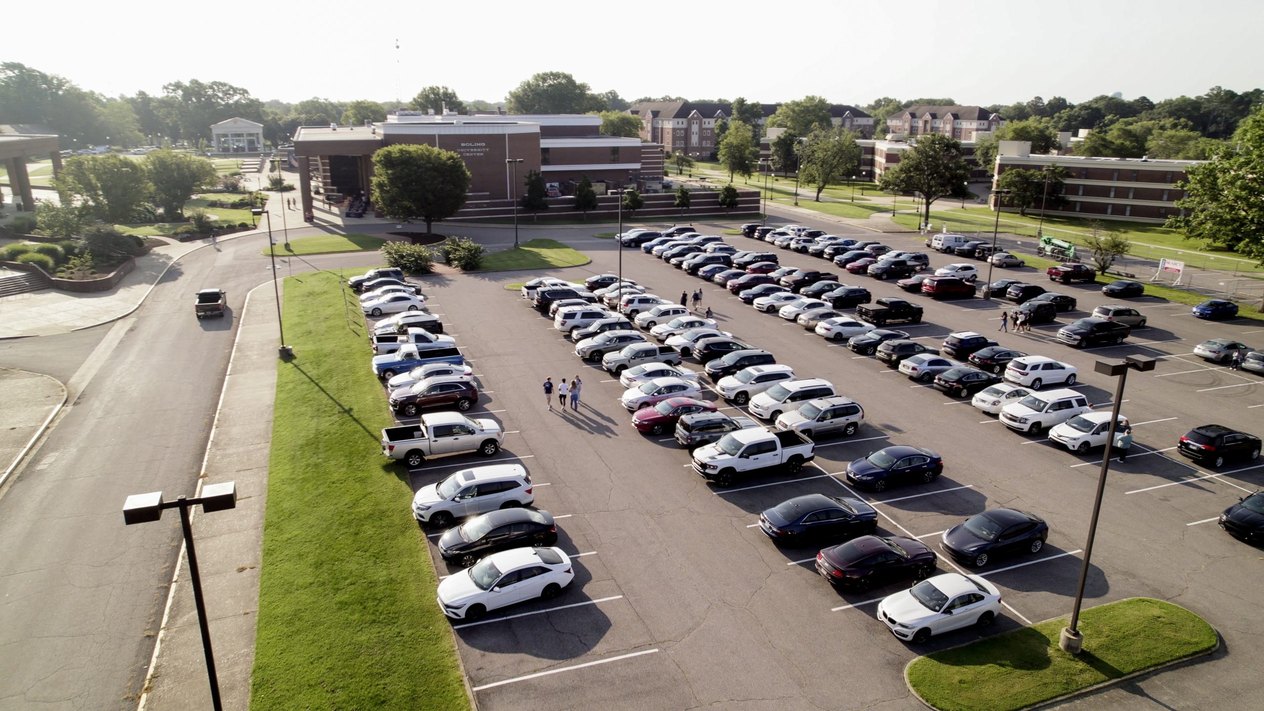 Several cars are shown in a full parking lot next to university buildings