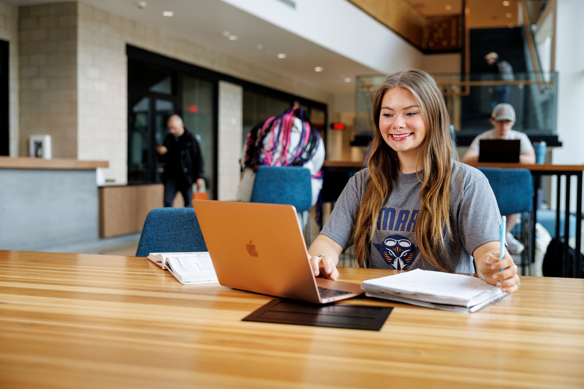 A female student smiles as she works on her laptop computer