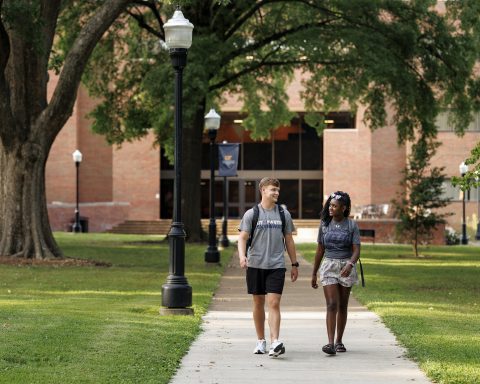 Two students are shown walking together on a college campus