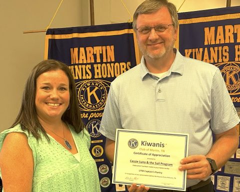 A woman and a man pose for a photo with the man holding a certificate