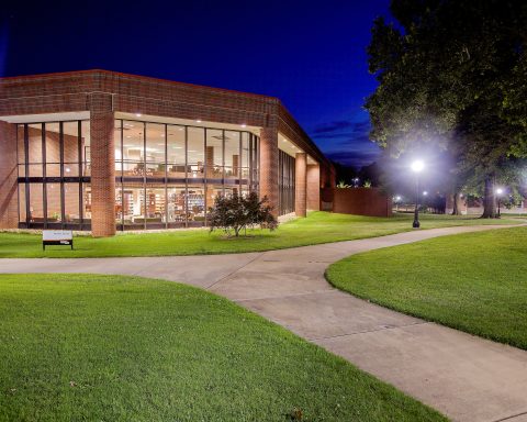 The outside of a college library is shown at night