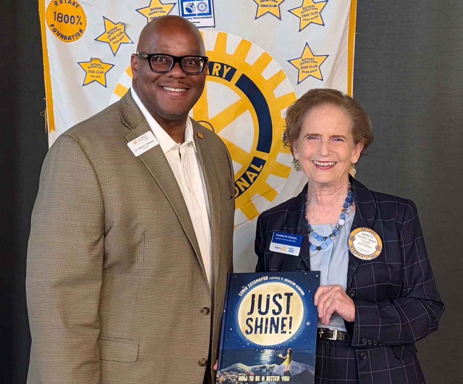 Two people are posed with one holding a book